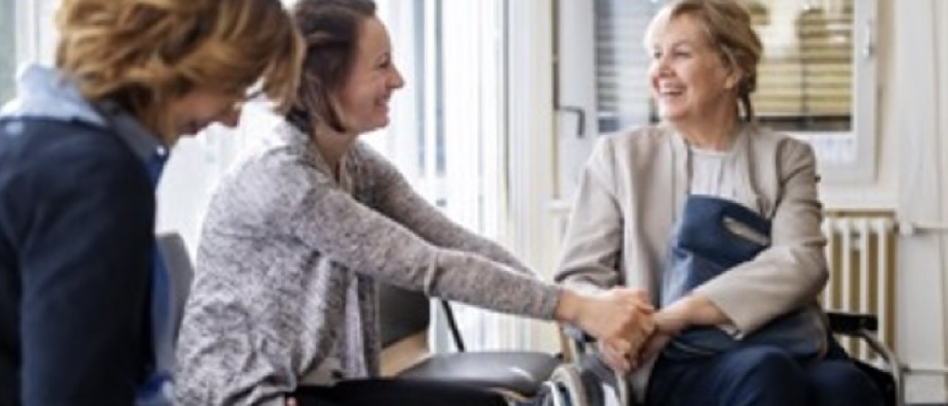 a person in a wheelchair shaking hands with a person in a white coat